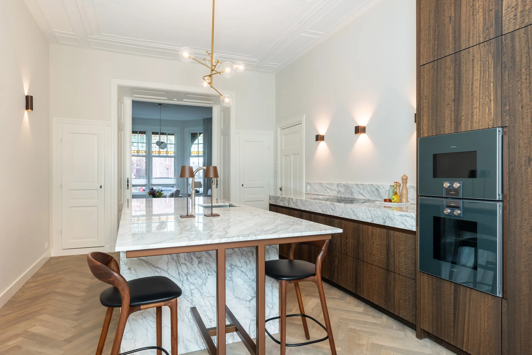 Eucalyptus kastenwand naast een licht marmeren eiland in een klassieke woning